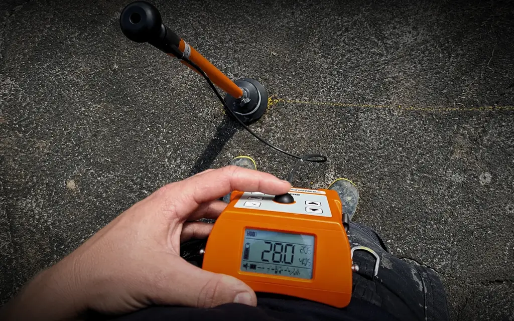 Technician using acoustic leak detection equipment to trace a hidden water leak